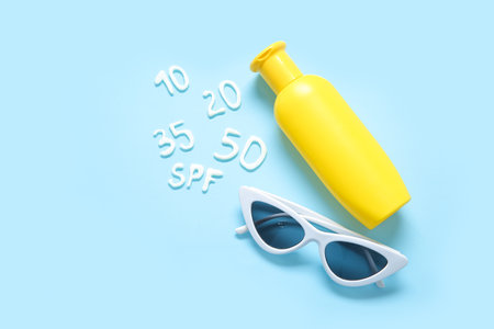 Word SPF with numbers made of sunscreen cream and sunglasses on blue backgroundの写真素材