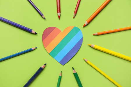 Paper heart with colorful pencils on green background. LGBT concept