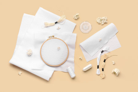 Wooden embroidery hoop with canvases, mouline threads and ball pins on pale orange background