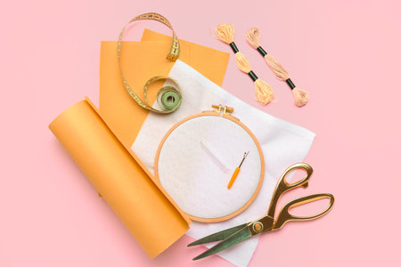 Embroidery hoop with canvases, mouline threads and measuring tape on pink backgroundの写真素材