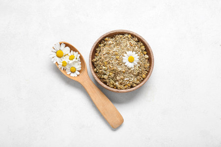 Bowl of dried and fresh chamomile flowers on light backgroundの写真素材