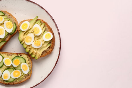 Tasty toasts with quail eggs, avocado and cucumber on light backgroundの写真素材