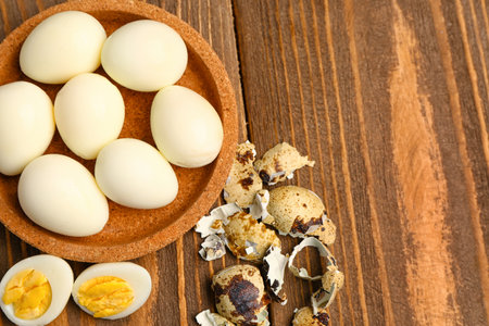 Bowl of boiled quail eggs with shells on wooden backgroundの写真素材