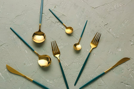 Golden set of cutlery with green handles on gray backgroundの写真素材