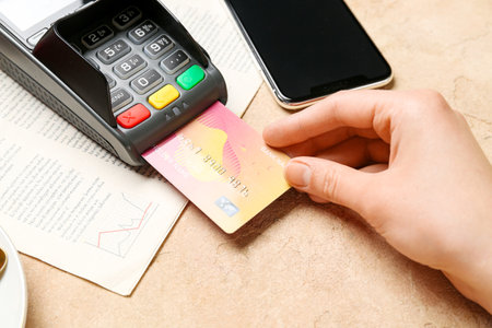 Young woman paying with credit card via payment terminal in cafeの写真素材