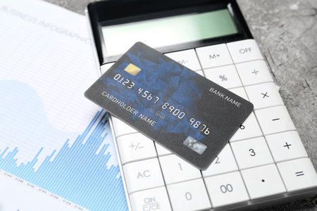 Credit card with calculator and business infographics on tableの写真素材
