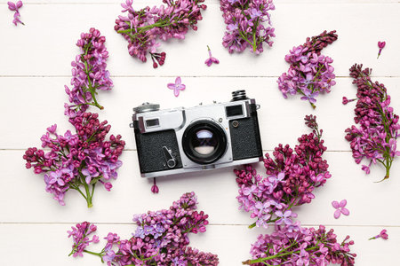 Lilac twigs with camera on white wooden table