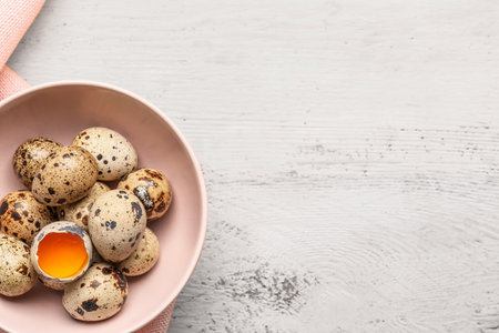 Bowl with fresh quail eggs on light wooden background, closeupの写真素材