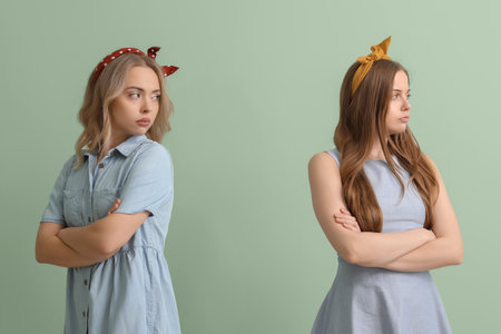 Upset young sisters on green backgroundの写真素材