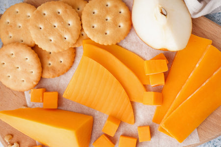 Board with tasty cheddar cheese, crackers and pear on table, closeupの写真素材
