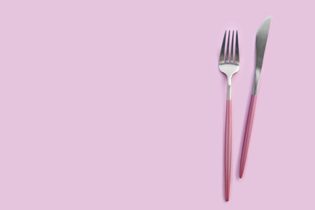 Stainless steel fork and knife on pink backgroundの写真素材