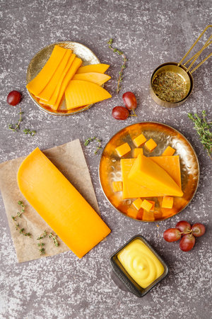 Composition with tasty cheddar cheese, grapes, sauce and herbs on grunge background