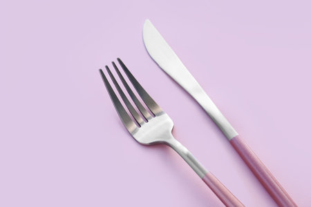 Stainless steel fork and knife on pink backgroundの写真素材