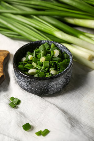 Bowl with fresh cut green onion on tableの写真素材
