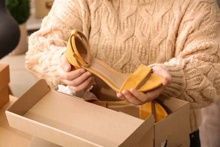 Woman taking out yellow suede shoes from box in roomの写真素材
