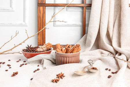 Composition with cinnamon sticks, coffee beans, anise stars and tree branch on light backgroundの写真素材