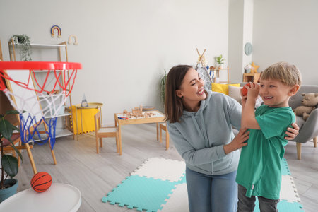 Nanny with little boy playing volleyball at homeの写真素材