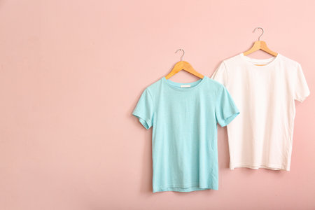 White and blue t-shirts hanging on pink wallの写真素材