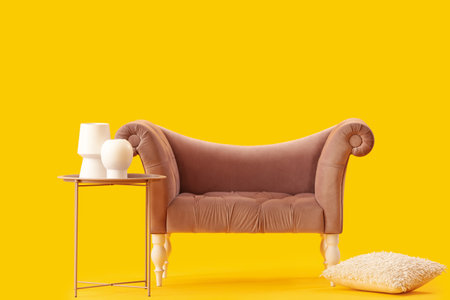 Stylish sofa and coffee table with vases on yellow backgroundの写真素材