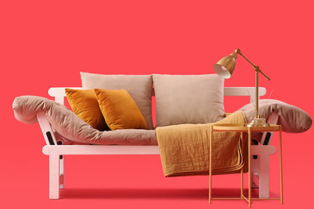 Cozy sofa and coffee table with lamp on red backgroundの写真素材