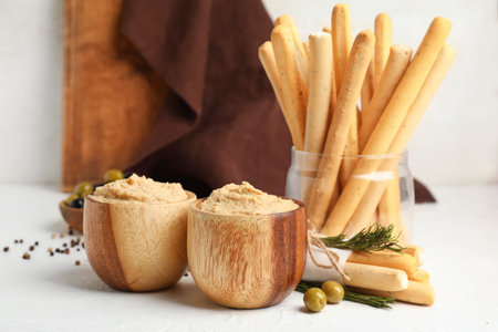 Bowls with tasty hummus and Italian Grissini on light backgroundの写真素材