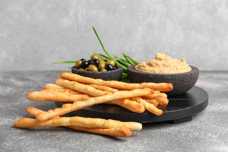 Wooden board with tasty Italian Grissini and hummus on grunge backgroundの写真素材