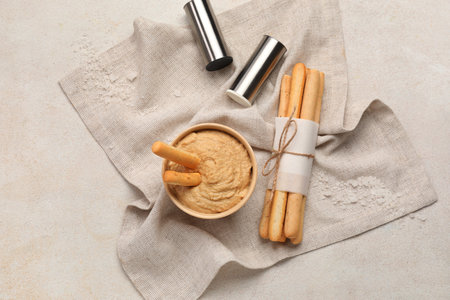 Bowl with tasty hummus and bunch of Italian Grissini on light background