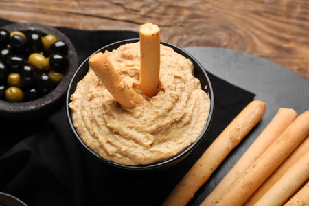 Bowl with tasty hummus and Italian Grissini on wooden backgroundの写真素材
