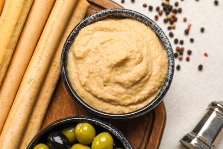 Bowl with tasty hummus and Italian Grissini on light backgroundの写真素材