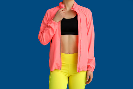 Sporty young woman in jacket on blue backgroundの写真素材