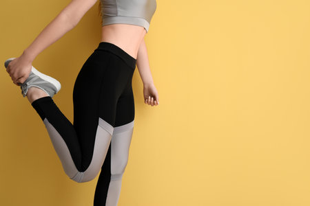 Sporty young woman in leggings on yellow backgroundの写真素材