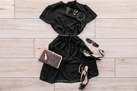 Black dress with accessories, heels and lipstick on light wooden floorの写真素材