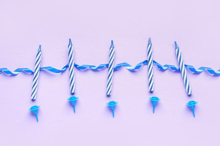Blue birthday candles and ribbon on lilac backgroundの写真素材