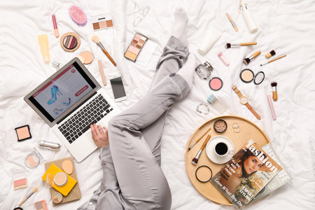 Woman with laptop, makeup products and accessories shopping online on white blanketの写真素材
