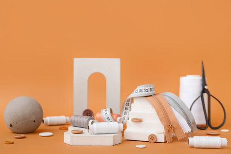 Podiums with tailor's supplies on orange background
