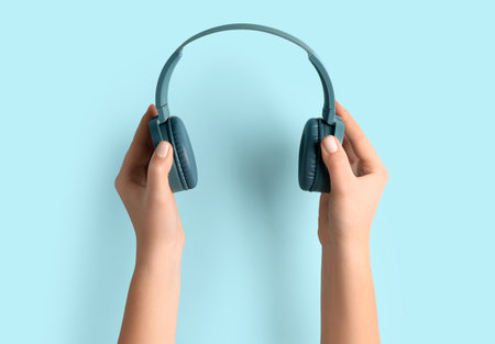 Woman holding modern headphones on blue backgroundの写真素材