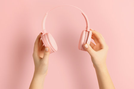 Woman holding modern headphones on pink backgroundの写真素材
