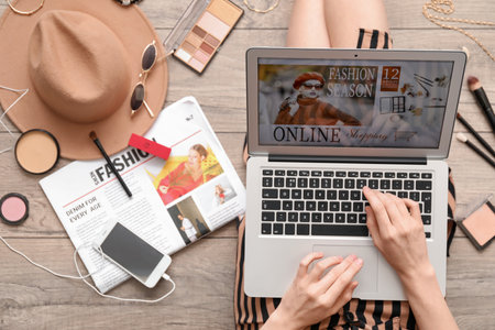 Woman with laptop, makeup products and accessories shopping online on light wooden floorの写真素材