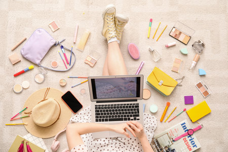 Woman with laptop, makeup products and accessories shopping online on beige carpetの写真素材