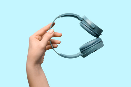 Woman holding modern headphones on blue backgroundの写真素材