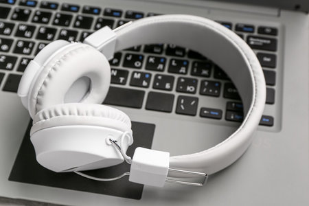 Modern white headphones on laptop, closeupの写真素材