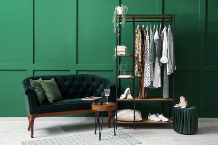 Interior of stylish room with sofa, shelving unit and clothesの写真素材