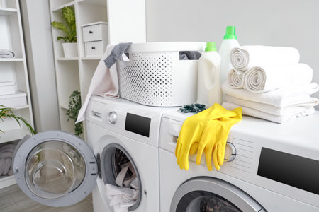 Basket with detergents and towels on washing machines in laundry room, closeupの写真素材