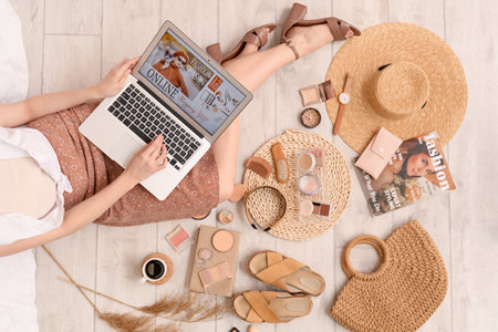 Woman with laptop and accessories shopping online on light wooden floorの写真素材