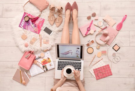 Woman with laptop, cup of coffee and accessories shopping online on light wooden floorの写真素材