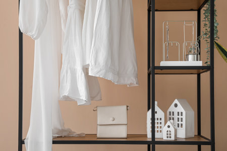 Shelving unit with clothes and accessories near beige wallの写真素材