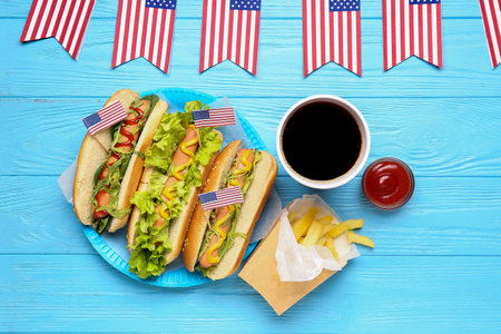 Composition with tasty hot dogs, french fries and cola on color wooden background. memorial day celebrationの写真素材