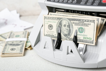 Modern cash counting machine with dollar banknotes on table, closeupの写真素材