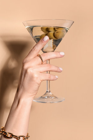 Woman with glass of martini on beige backgroundの写真素材