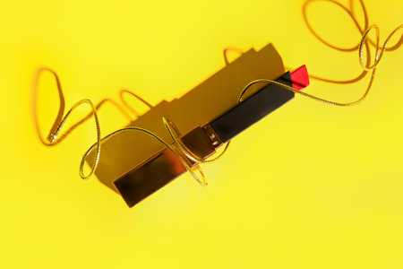 Beautiful lipstick with golden rope on yellow backgroundの写真素材